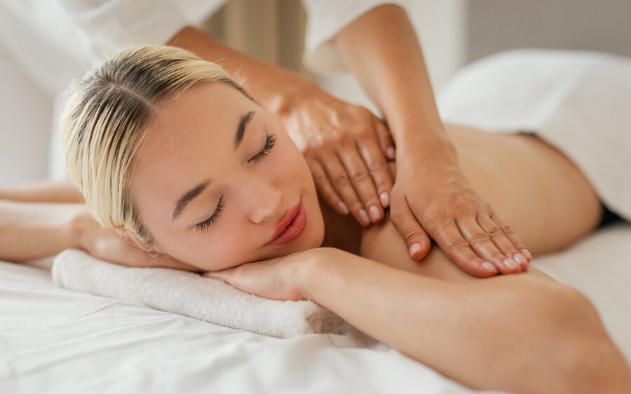 Woman enjoying a relaxing full body Swedish massage with hands applying pressure to shoulders - ano medical spa
