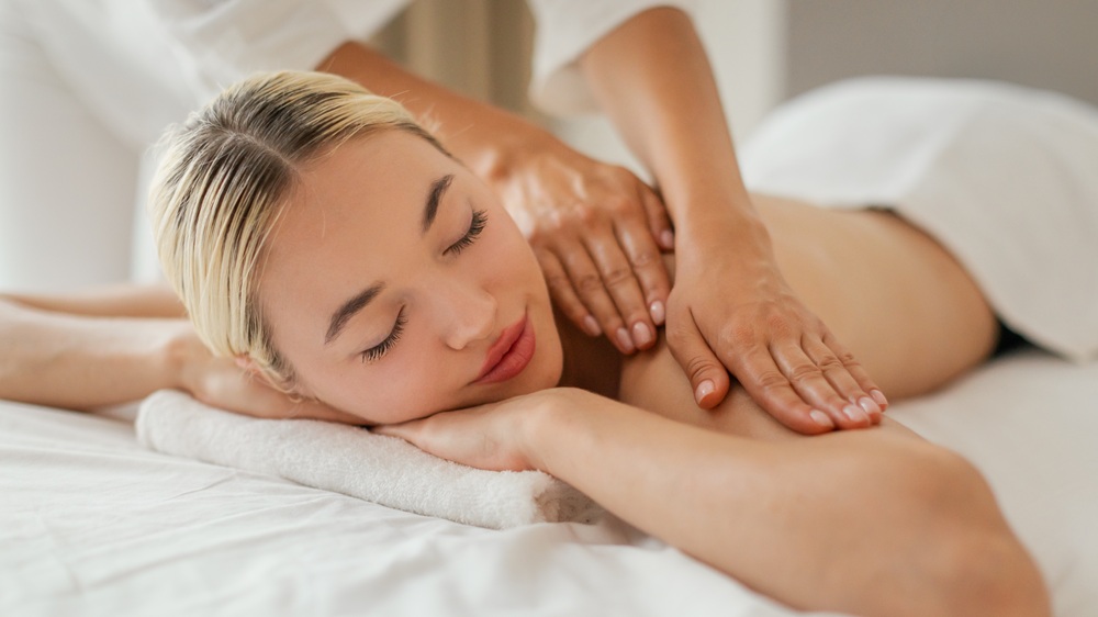 Woman enjoying a relaxing full body Swedish massage with hands applying pressure to shoulders - ano medical spa
